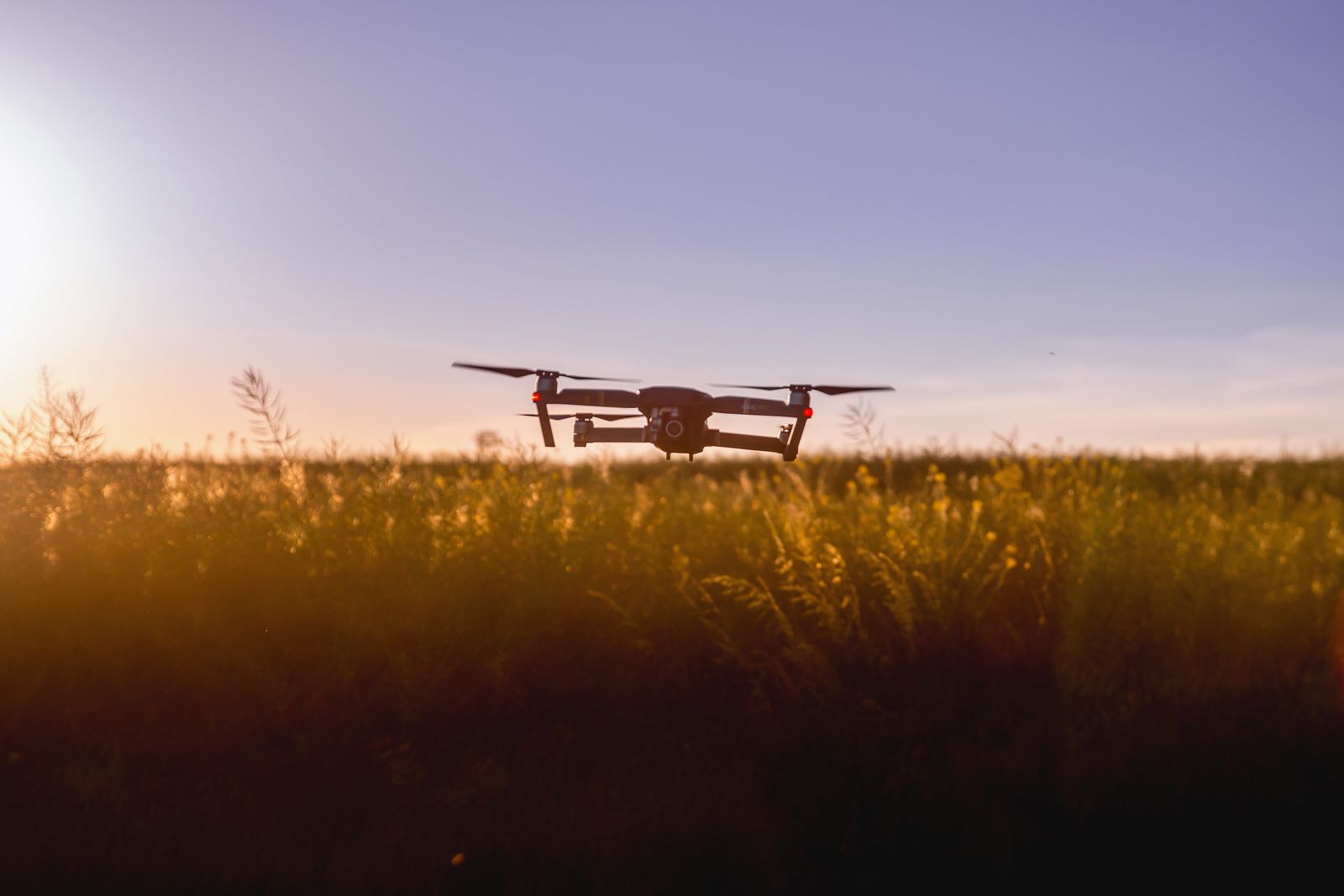 Drone flying over a green field during sunset with stunning aerial views